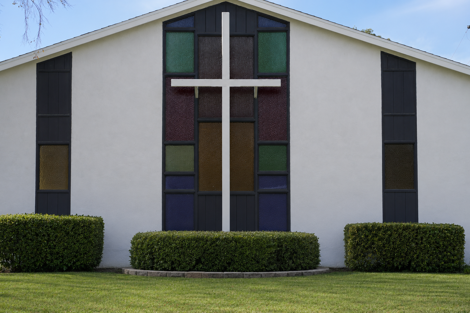 The front of Banning Lao Evangelical Church — white stucco facade with a tall stained-glass window and a white cross